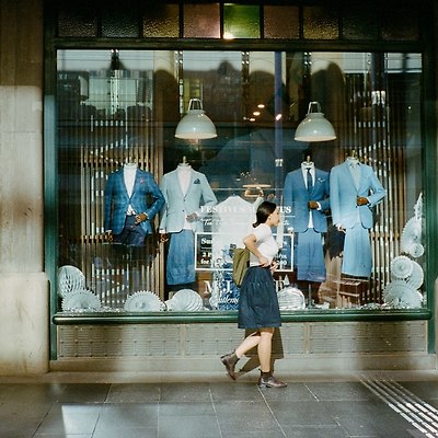 낮 사진 찍는 동안 보도 위를 걷는 파란 드레스를 입은 여자.